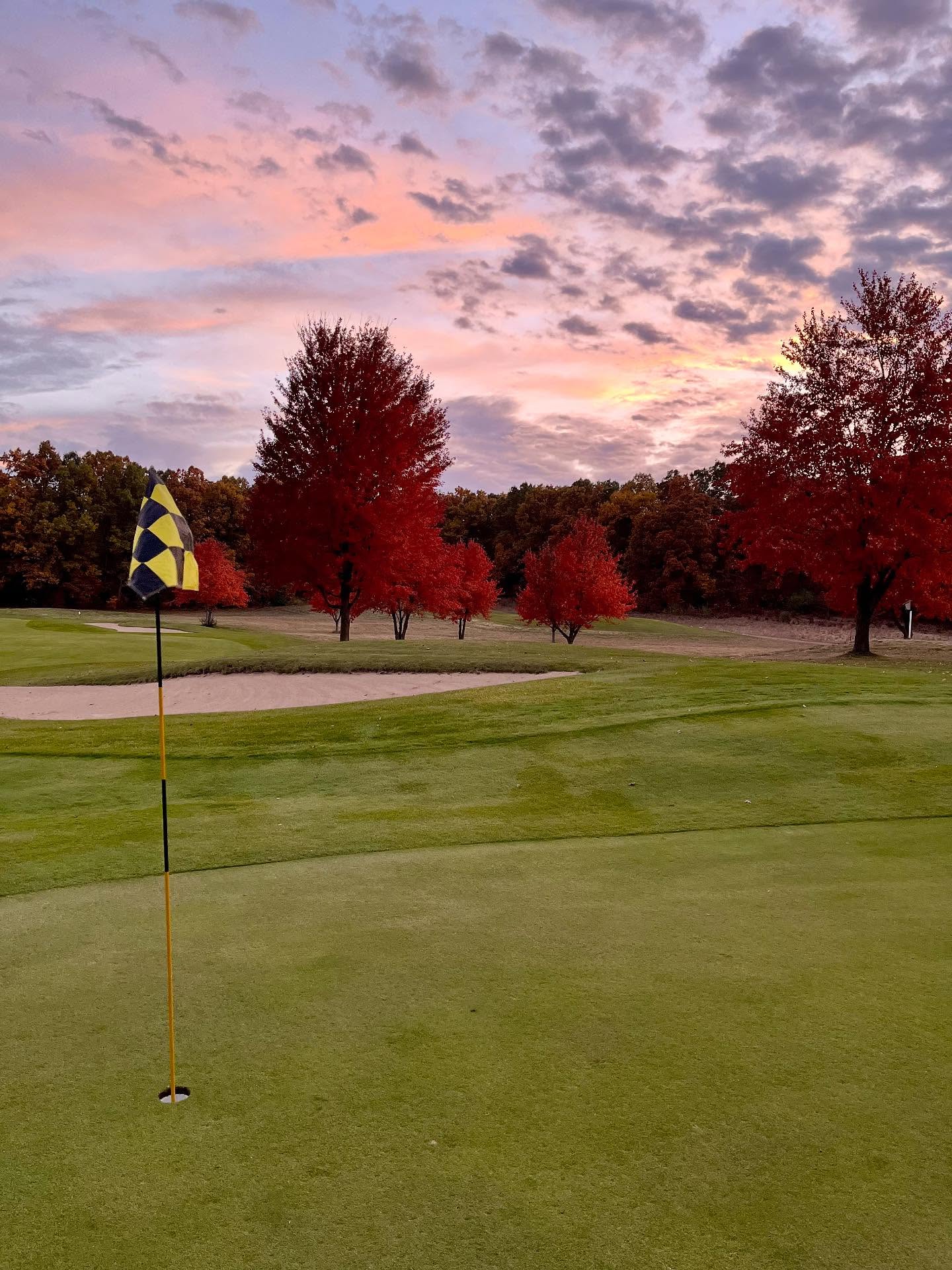 Golf course hole on fairway at sunset